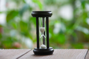 time limit minute glass on table with green trees in the background. 